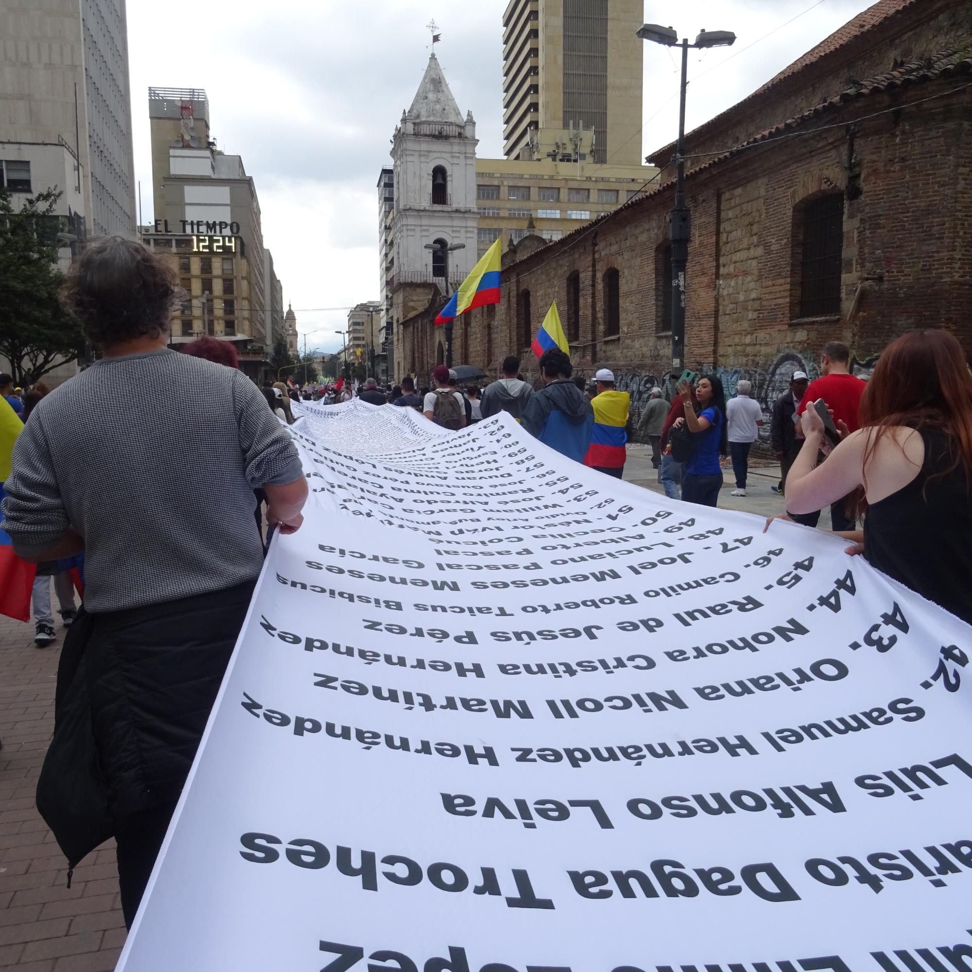Demonstration in Bogotá für Umsetzung des Friedensvertrags und gegen Morde an Menschenrechtsaktivist_innen. Ein Banner mit den Namen von ermordeten Aktivist_innen wird ausgebreitet. (21.11.2019)