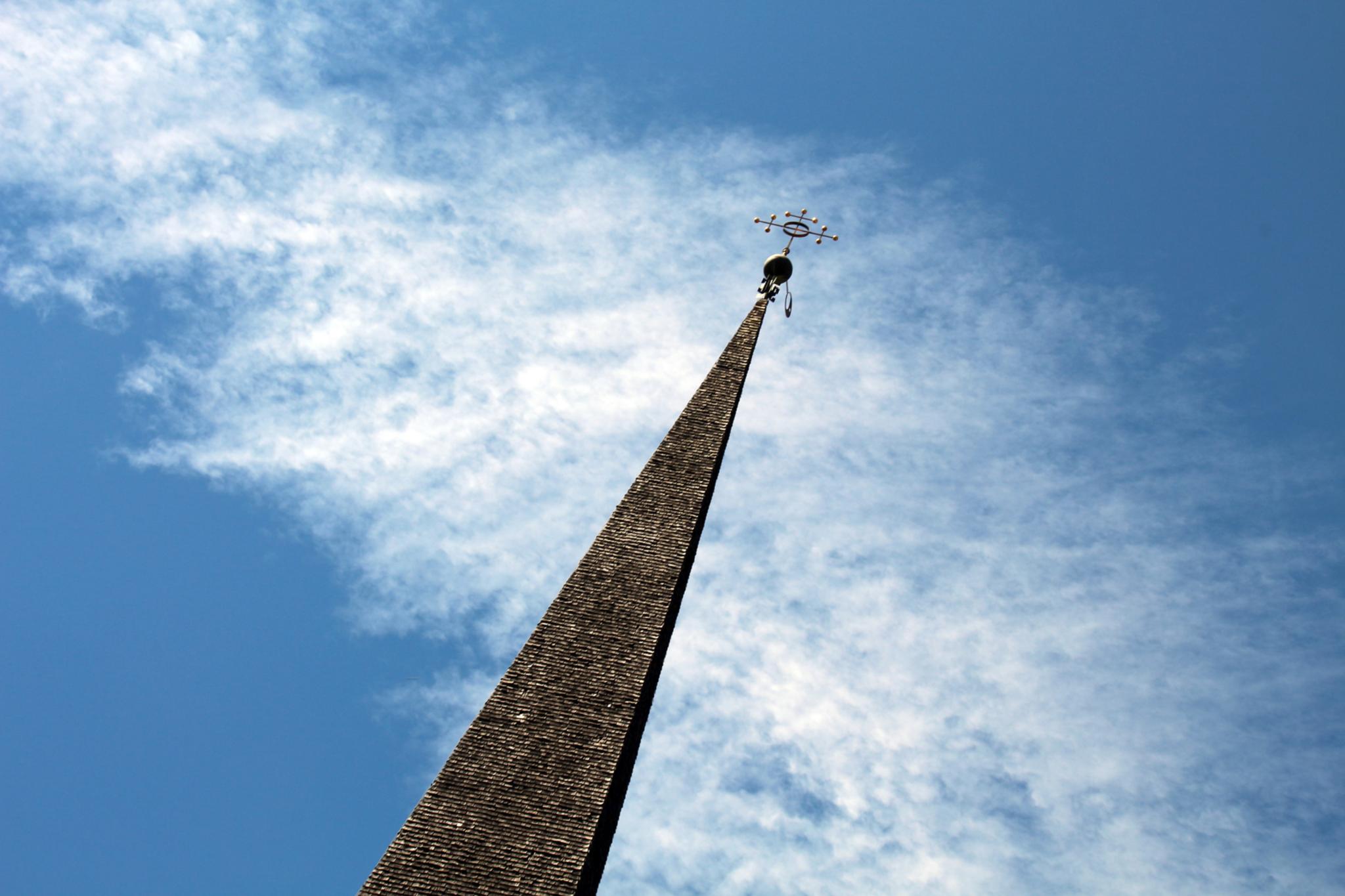 Kirchturm ragt vor dem Himmel auf, in der Perspektive ist er nach rechts geneigt.