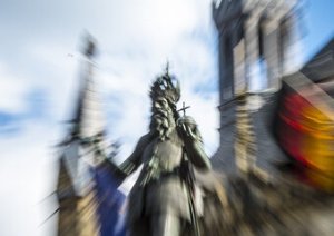 Verwischtes Bild der Statue Kaiser Karls vor dem Aachener Rathaus mit Europaflagge und Deutschlandflagge)