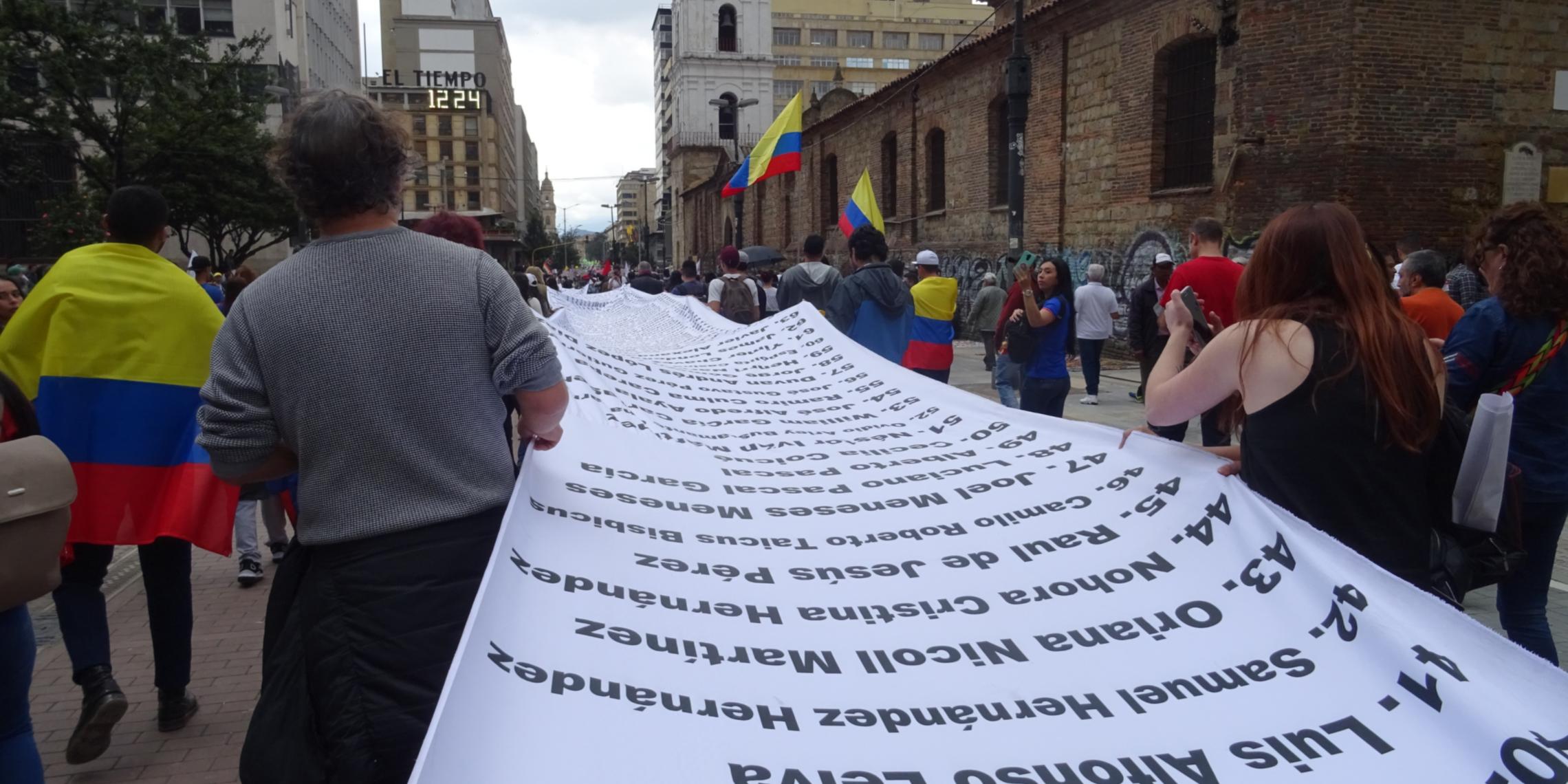 Demonstration in Bogotá für Umsetzung des Friedensvertrags und gegen Morde an Menschenrechtsaktivist_innen. Ein Banner mit den Namen von ermordeten Aktivist_innen wird ausgebreitet. (21.11.2019)