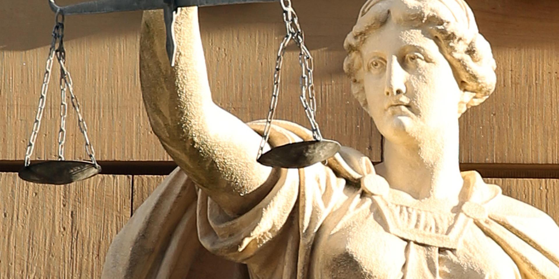 Eine Skulptur aus Stein, die das klassische Motiv von Justitia zeigt.