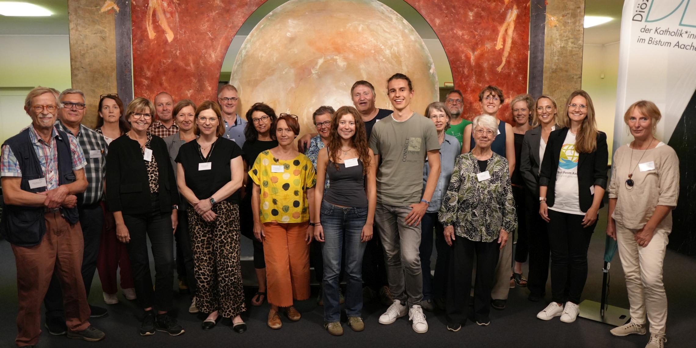 Viele Menschen stehen in einer Gruppe zusammen und schauen in die Kamera.